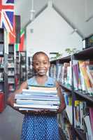 Girl smiling while carrying books in library