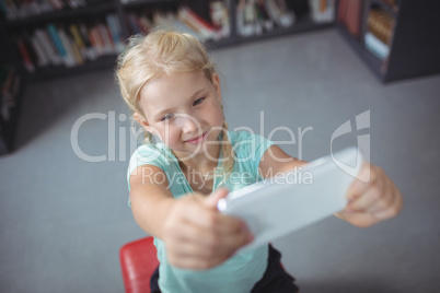 Girl using mobile phone while sitting in library