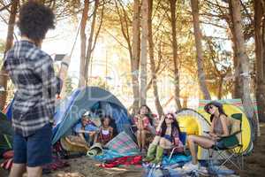 Man photographing smiling friends at campsite