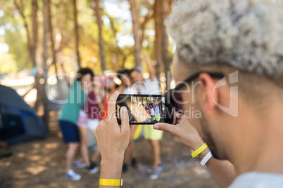 Close up of man photographing friends with smartphone