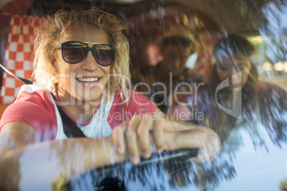 Smiling friends in camper van seen through windshield