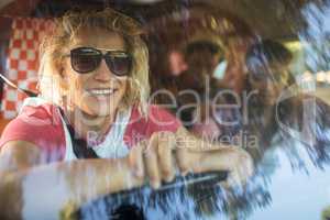 Smiling friends in camper van seen through windshield