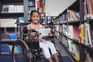 Girl on wheelchair smiling while holding digital tablet