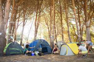 Friends setting up colorful tents at campsite