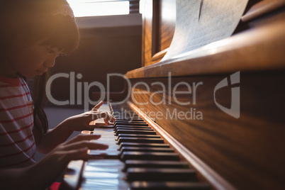 Focused girl practicing piano in classroom