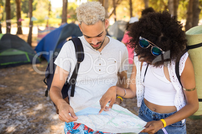 Friends reading map while standing on field