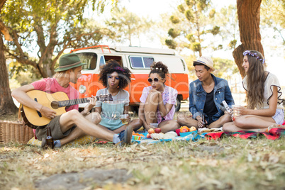 Friends listening to man playing guitar