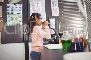 Side view of elementary schoolgirl looking through microscope at laboratory