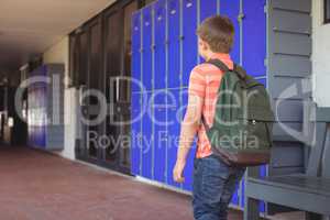Rear view of boy with backpack walking in corridor