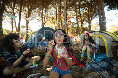 Young woman blowing bubble wand at campsite