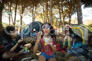 Young woman blowing bubble wand at campsite
