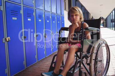 Portrait of schoolboy sitting on wheelchair in corridor
