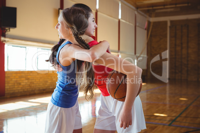 Smiling female player embracing in basketball court