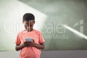 Boy using cellphone against greenboard in school