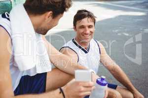 Basketball player showing mobile phone to friend
