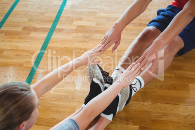 Friends exercising while sitting on hardwood floor