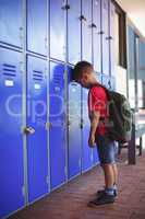 Side view of boy leaning on lockers in corridor