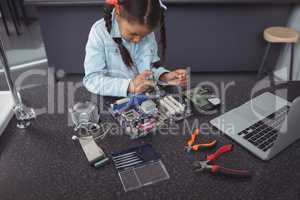 High angle view of concentrated elementary girl assembling circuit board