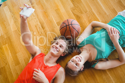 Overhead view of man taking selfie while lying with female friend