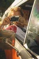 Man photographing through camera while sitting in van