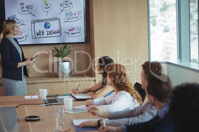 Businesswoman explaining plant to team during meeting