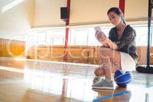 Woman using mobile phone in basketball court