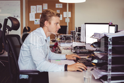 Side view of businessman working on computer at desk