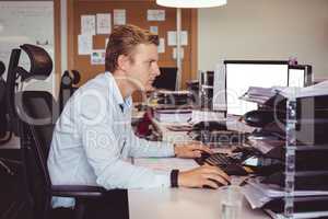 Side view of businessman working on computer at desk