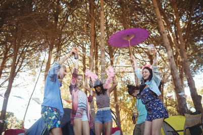 Low angle view of friends dancing against trees at campsite