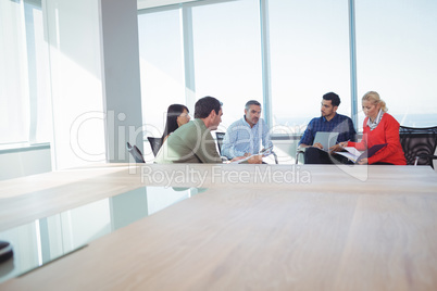 Business colleagues discussing while sitting against window at office