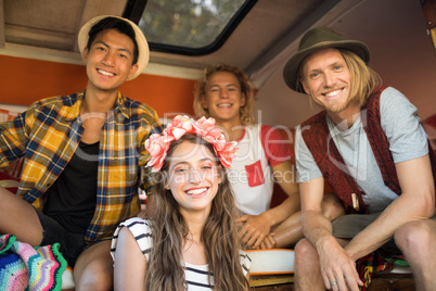 Smiling young friends sitting together in camper van