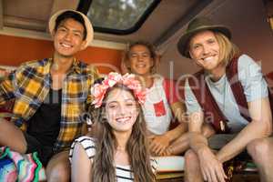 Smiling young friends sitting together in camper van