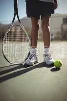 Girl with tennis racket and ball on court