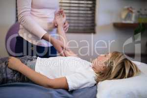Midsection of female therapist examining arm with boy lying on bed