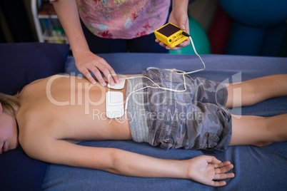 High angle view of female therapist placing electrodes on back