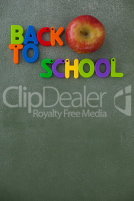 Block letters and apple arranged on chalkboard