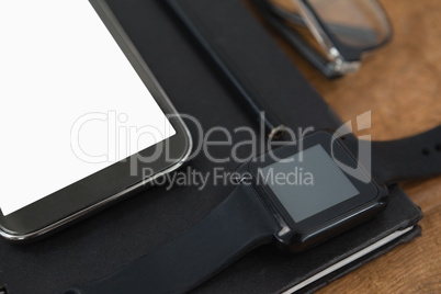 diary, smart watch, pencil, smartphone and spectacles on wooden background