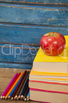 Stack of books, apple and color pencils