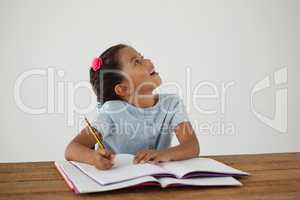 Young girl writing in her book against white background