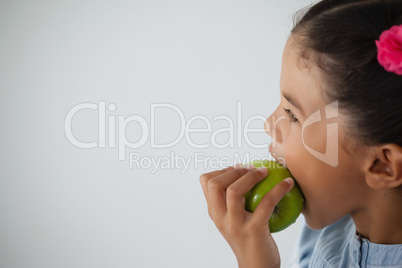 Schoolgirl eating apple against white background