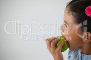 Schoolgirl eating apple against white background