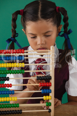 Schoolgirl using abacus against chalkboard