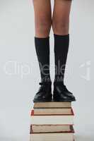 Low-section of schoolboy standing on books stack