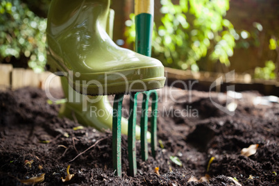 Close-up low section of woman standing with fork on dirt