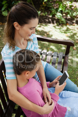 High angle view of woman looking at daughter using mobile phone while sitting on bench
