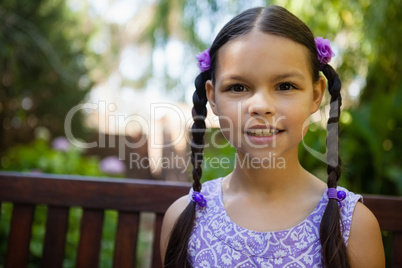 Close-up portrait of smiling girl sitting on bench