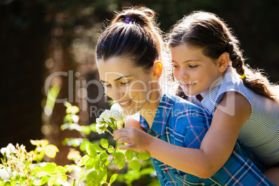 Daughter smelling rose with mother while enjoying piggyback