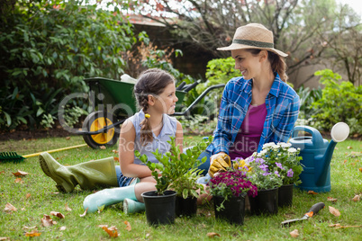 Smiling mother and daughter sitting with various potted plants