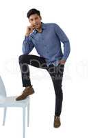 Portrait of young businessman stepping on chair