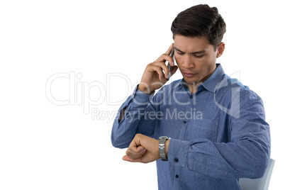 Businessman looking time while talking on smartphone